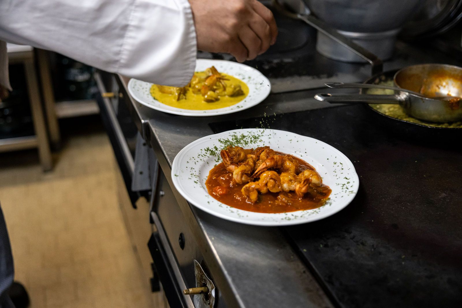 Deux assiettes dressées au passe : sauce tomate aux scampis et plat à la crème